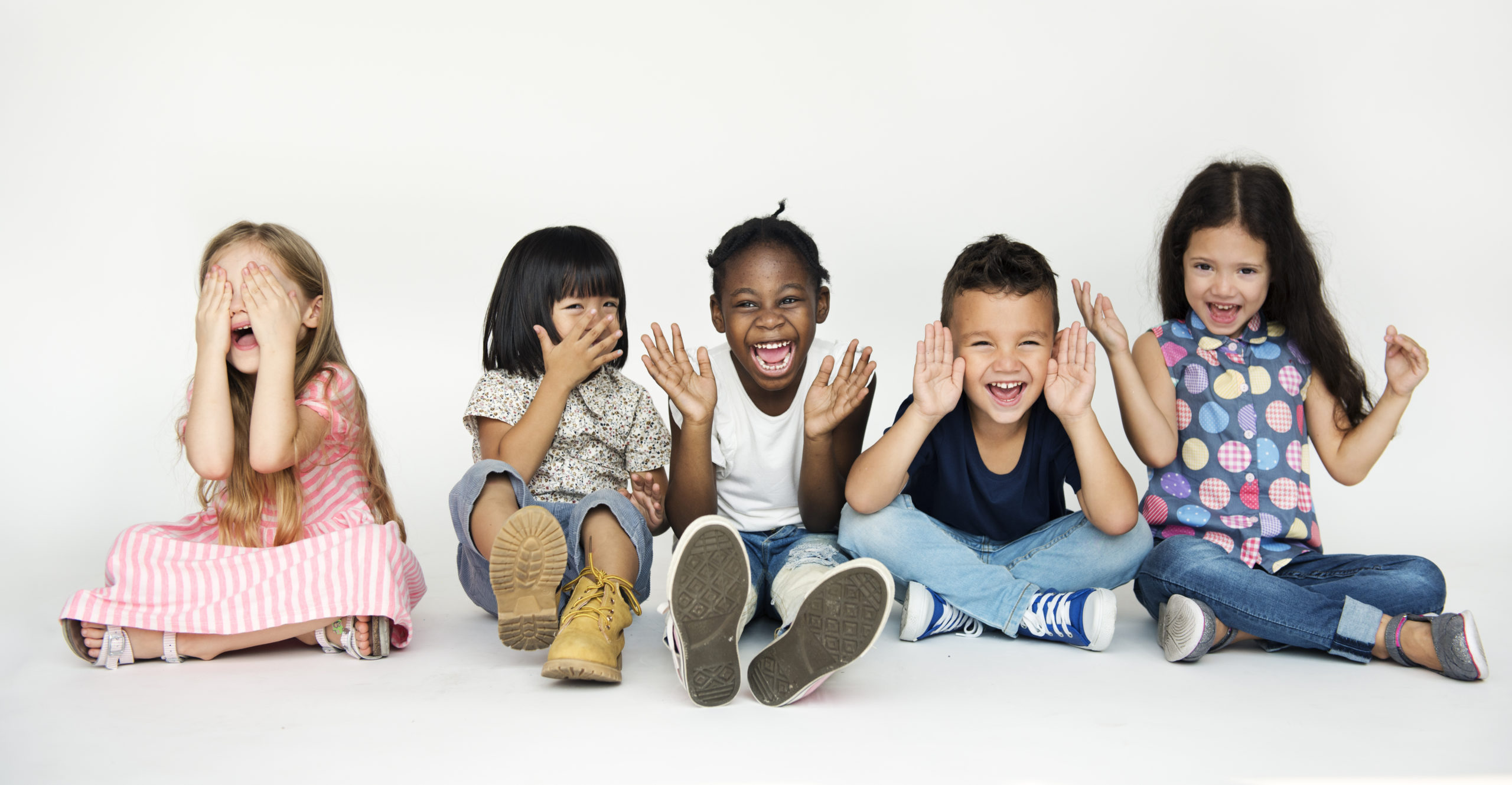 Happy smiling diverse group of kids sitting down cross-legged